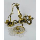 A small crystal chandelier light together with a three branch brass chandelier