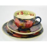 A Moorcroft cup, 6cms tall, and saucer trio, in the pomegranate pattern, impressed with the Cobridge