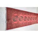 A 19th century runner with dark red ground, and black decorated borders and central motifs, 79 by