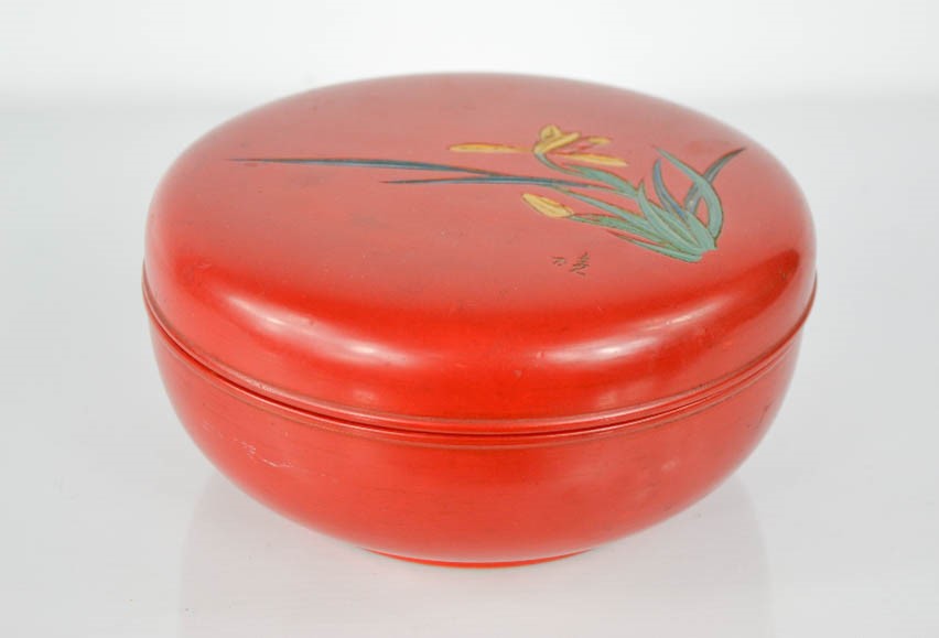 A Japanese red lacquered box, engraved with a flower and signature, 20cm diameter.