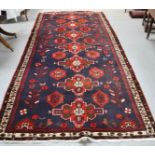 A 19th century rug, with blue ground, dark red borders and red motifs, 152 by 357cm.