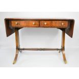 A 19th century rosewood sofa table, with two drawers, hinged drop leaves and raised on brass caps