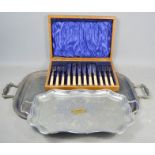 Two large silverplate trays together with a cased set of silverplate cutlery.