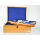 A canteen of cutlery, the campaign style oak box opens to reveal three layers of flatware, blue