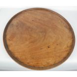 A 19th century mahogany tray, with raised edge, previously a table top, 51cm diameter.