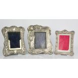 Three silver photograph frames, each embossed with decoration, the largest measures 22 by 18cm.