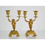 A pair of 19th century gilt candelabra, in the form of classical putti figures holding the candle