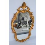 A gold painted wall mirror, with scrollwork frame, 96cm high.