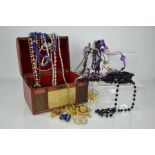 A domed jewellery box containing costume jewellery, including necklaces and brooches.