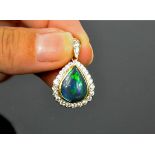 An 18ct (unmarked) gold and black opal and diamond pear form pendant, the opal 4.02ct bordered by