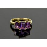 A 9ct yellow gold and amethyst trilogy ring, with emerald cut amethysts, size Q, 2.7g.