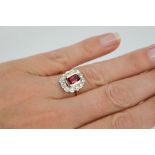 An 18ct yellow gold, ruby and diamond ring, the cushion cut 1ct ruby bordered by 0.60cts, size N,