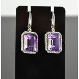 An 18ct white gold, diamond and amethyst drop earrings, the cushion cut amethysts bordered by