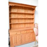 A pine dresser and enclosed rack, with three drawers above cupboard doors. 211cm high x 156cm wide x