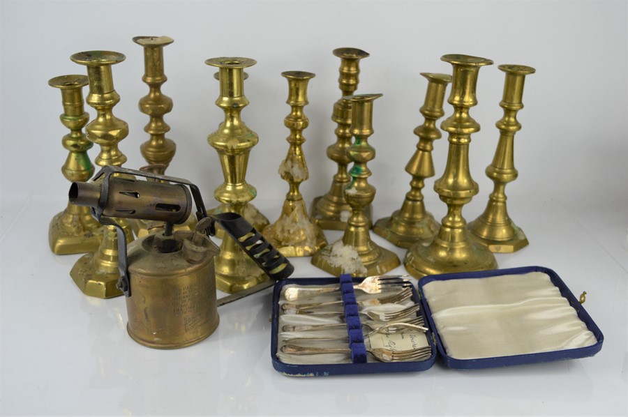 A group of brass candlesticks together with a brass blow torch and EPNS spoons