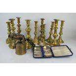 A group of brass candlesticks together with a brass blow torch and EPNS spoons