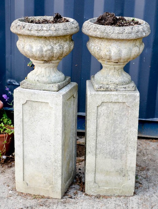 A pair of stone garden urns on pedestals.