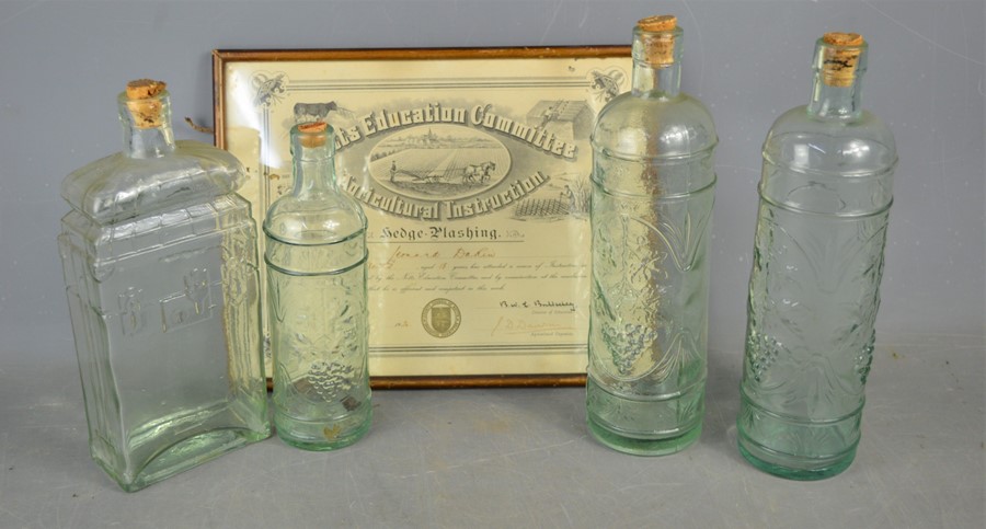 Four wine / brandy bottles with decorated front together with a framed certificate for hedge