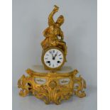 A French gilt metal mantle clock with roman numeral barrel dial surmounted by a seated figure -
