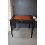 An Empire style ebonised games table, with rotating marquetry chess top, raised on square tapered