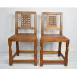 A pair of Robert Thompson 'Mouseman' lattice back dining chairs with leather seats, both carved with