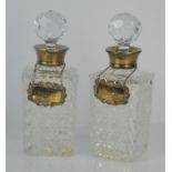 A pair of cut glass Scotch and Brandy decanters with silver hallmarked collars and tags