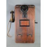 An antique wall mounted telephone in a solid oak box