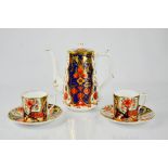 A Royal Crown Derby coffee pot and cover, and two cups and saucers, The Purdol Collection.