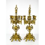 A pair of brass candleabra, with five candle sockets, raised on decoratively cast bases.