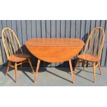 An Ercol dining table and two matching chairs.