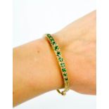 A 9ct gold [unmarked] emerald and diamond bangle. 12.2g