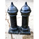 A pair of black painted reconstituted stone bollards.