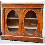 A 19th century walnut credenza with ormolu mounts, oval glazed cupboard doors enclosing two shelves,