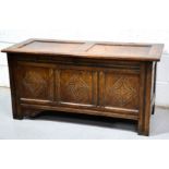 An 18th century oak coffer, with three carved front panels, run moulded rails and stile feet, 57