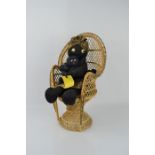 A Zulu woman doll with baby sitting in a wicker chair.