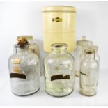 A group of glass jars with covers, some with labels, and a tin box.