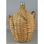 Green glass demijohn in wicker basket