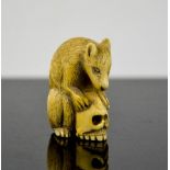 A Chinese ivory carved netsuke in the form of a wolf cub and skull, signed to the base, 4cm high.