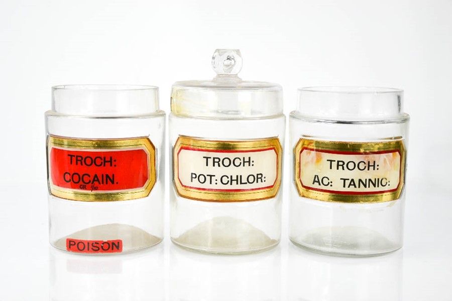 Three glass apothecary jars, bearing labels, 19cm high.