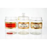 Three glass apothecary jars, bearing labels, 19cm high.