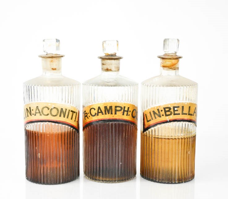 Three antique glass apothecary bottles, each having latin labels, 20cm high.