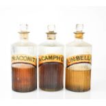 Three antique glass apothecary bottles, each having latin labels, 20cm high.