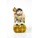 An early 20th century Chinese ceramic man raised on a barrel, 16cm high.