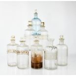 Eight antique glass apothecary jars, each with contents labels and with stoppers, 20cm high.