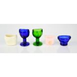 Five vintage eye baths, including three glass examples.