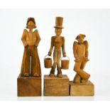 Three German treen carvings, comical figures raised on plinths, one engraved Hummel, M.M, tallest