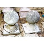 Two stone garden balls on pedestal bases.