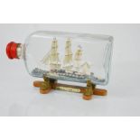 A Chinese glass ship in a bottle on stand, 25cm long.