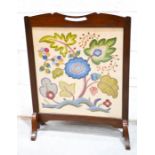A mahogany fire screen with a needlework panel.