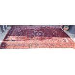 A large red ground rug, Middle Eastern origin, in wool, depicting various stylized motifs.